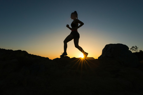 Silhouette of woman running over rocks