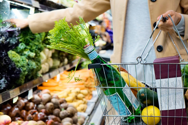 Person putting vegetables in supermarket basket