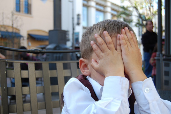 Small boy covering his face with hands