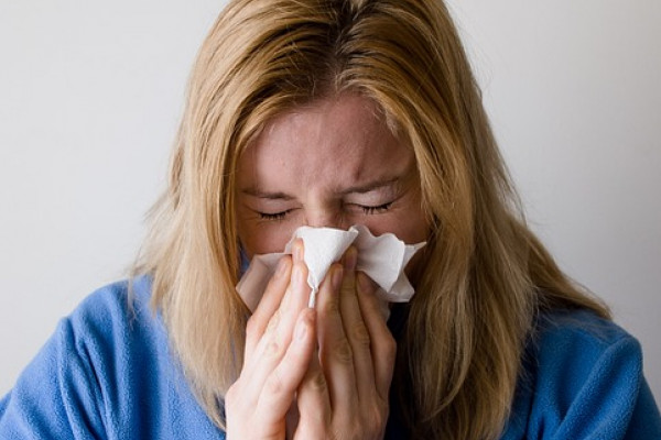 A woman sneezing into a tissue.