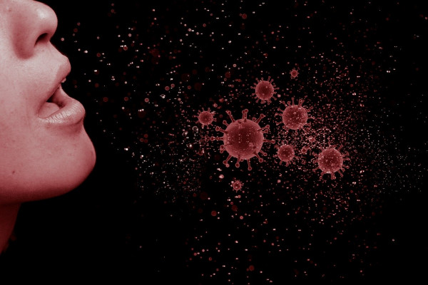 A graphic showing a face mid-cough and some virus particles.