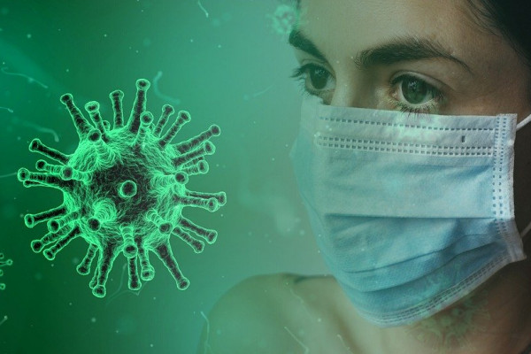 A stylised coronavirus particle next to a woman wearing a facemask.
