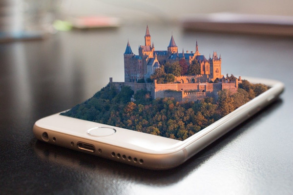 A smartphone with a castle and forest coming out of the screen in 3D.