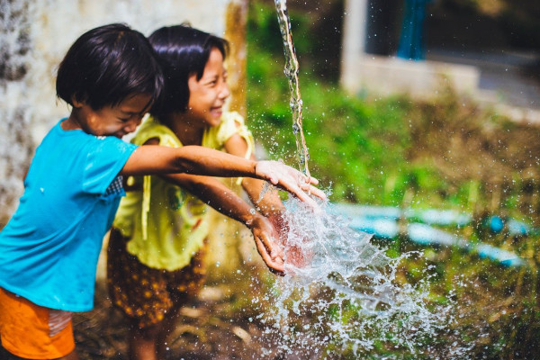 a photo of children smiling by a water fountain