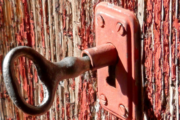 A rustic key partly turned in a lock on a door.
