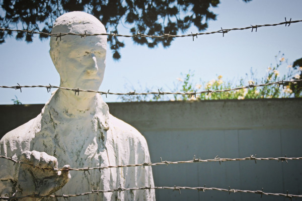Holocaust memorial statue of a man standing behind barbed wire