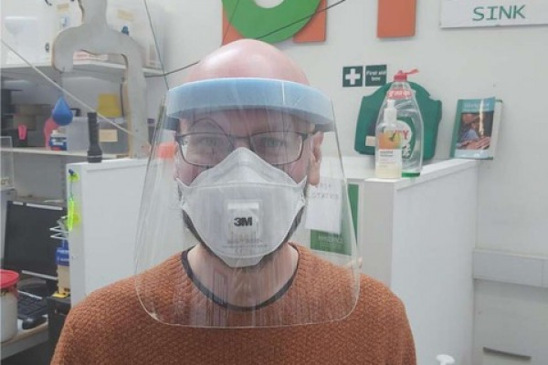 A Makespace volunteer wearing a plastic face visor.