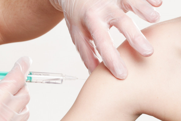 A patient receives a vaccination into their arm