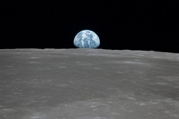 a photo taken from the surface of the moon, looking at Earth as it rises