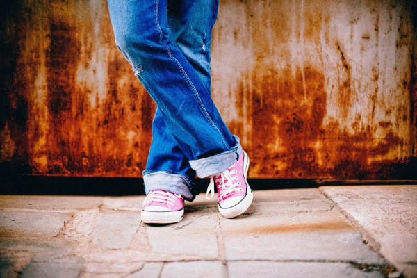 a photo of someone's legs, wearing jeans and trainers