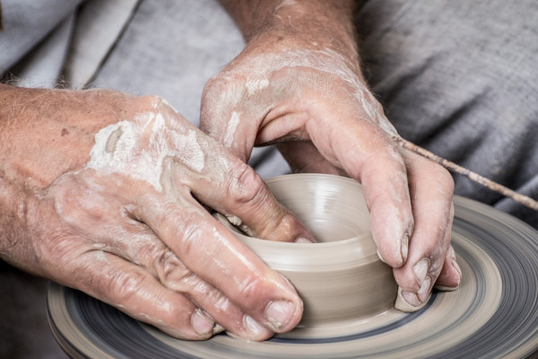 A potter working some clay on a wheel.