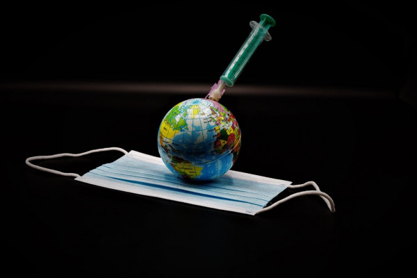 A globe lying on a facemask with a syringe stuck into it.