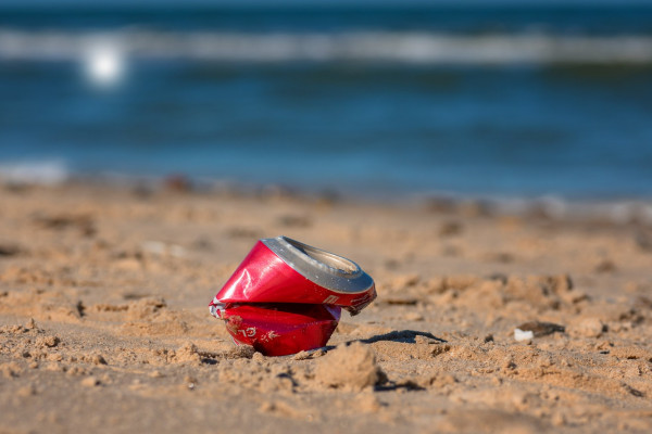 A crushed drinks can on a beach.