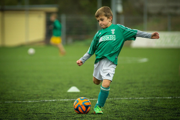 A young boy kicking a football.