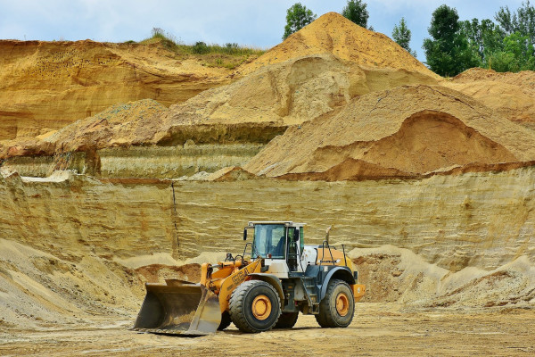 A bulldozer in front of a piled up sand quarry