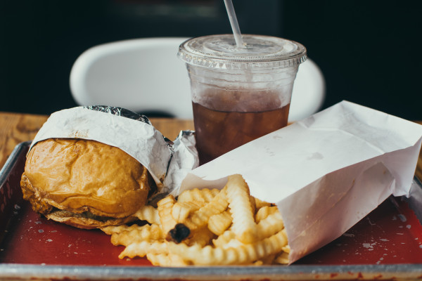 A tray with a burger, chips, and soft drink.