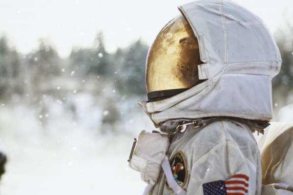 An astronaut in a snowy setting in profile, looking up at the sky