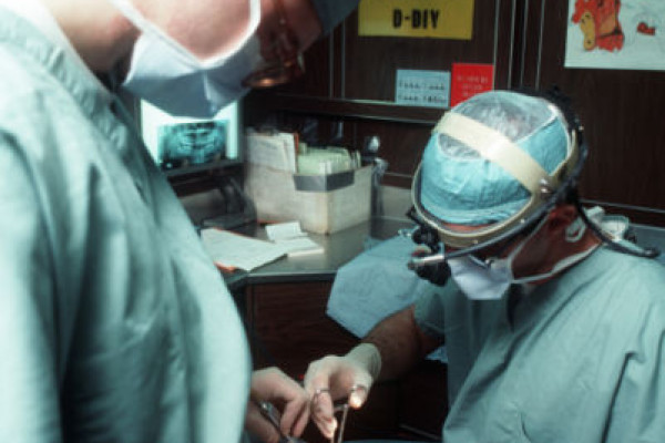 A dental officer and his assistant remove the wisdom tooth of a crew member of the nuclear-powered aircraft carrier USS DWIGHT D. EISENHOWER (CVN-69) during Fleet Ex 1990.