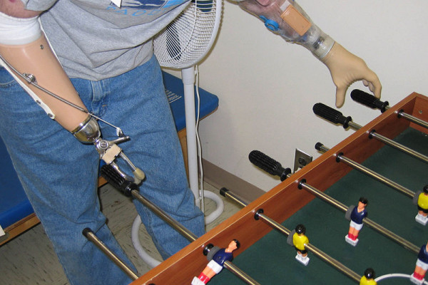 A soldier in the U.S. Army plays fooz-ball with two prosthetic limbs.