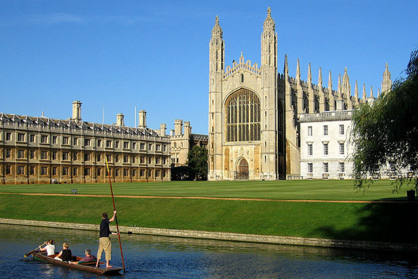 The west end of King's College Chapel seen from The Backs. Clare College Old Court is on the left. A group of people punting along the River Cam can be seen in the foreground.