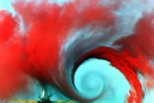  The air flow from the wing of this agricultural plane is made visible by a technique that uses colored smoke rising from the ground. The swirl at the wingtip traces the aircraft's wake vortex, which exerts a powerful influence on the flow field...