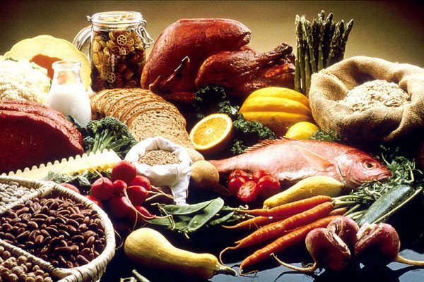  This image shows a display of healthy foods on a table. Foods include beans, grains, cauliflour, cantelope, pasta, bread, orange, turkey, salmon, carrots, turnips, zucchini, snowpeas, string beans, radishes, asparagus, summer squash, lean beef,...