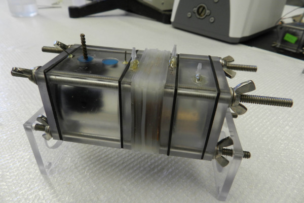  The microbial electrolysis cell (MRC) used in the study, shown empty. You can see the graphite fiber brush anode in the left chamber, the reverse electrodialysis (RED) stack in the middle (only the gaskets holding the membranes are visible), and the...