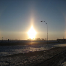 Very bright sun dogs in Fargo, North Dakota. Also visible are parts of the 22° halo (the arcs passing through each sundog), a sun pillar (the vertical line) and the parhelic circle (the horizontal line).