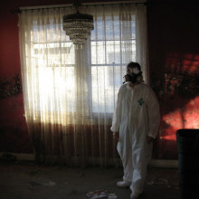 Man in hazard suit next to curtains
