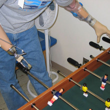 A soldier in the U.S. Army plays fooz-ball with two prosthetic limbs.