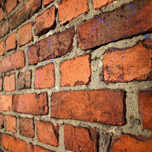 An old brick wall in English bond laid with alternating courses of headers and stretchers.