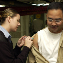 Hospital Corpsman 3rd Class Tiffany Long administers the influenza vaccination to a crew member aboard USS Kitty Hawk