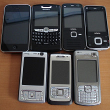 Assorted smartphones. From left to right, top row: iPhone 3G, Blackberry 8820, Nokia N78, Nokia N81, (bottom row) Nokia N95, Nokia E65, Nokia N70.