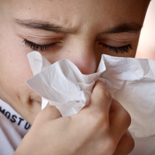 A person with a cold, sneezing into a hacky