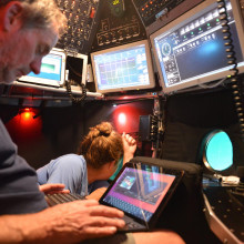 Inside the Alvin. Our Alvin pilot Bob Waters working on communicating with the surface and me staring out my port window.