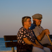 An elderly couple sitting together looking out to sea