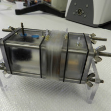  The microbial electrolysis cell (MRC) used in the study, shown empty. You can see the graphite fiber brush anode in the left chamber, the reverse electrodialysis (RED) stack in the middle (only the gaskets holding the membranes are visible), and the...