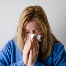 A woman sneezing into a tissue.