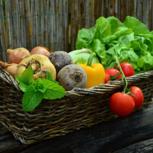 A wicker basket filled with an assortment of different vegetables
