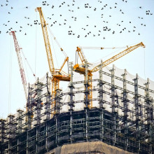 A skyscraper under construction with cranes on the roof