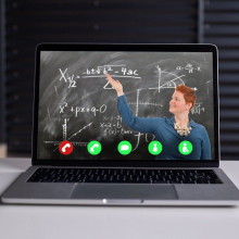 image of teacher next to blackboard, via video call