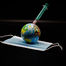 A syringe sticking out of a globe, lying on a facemask.