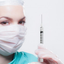 A healthcare worker wearing a mask holding a syringe.