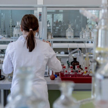 A woman with her back to the camera in a lab, using scientific equipment