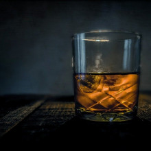 Whisky A tumbler of whisky on a table against a dark blue background