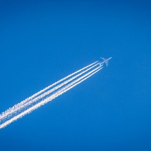 A plane flying across the sky, leaving a streaky contrail cloud behind it