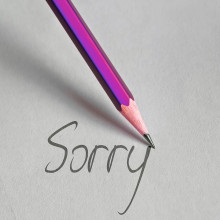 a purple pencil writing the word "sorry" on paper