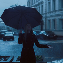 A girl holding an umbrella checks if it is still raining