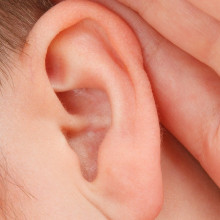 a close up of someone with their hand to their ear, trying to listen