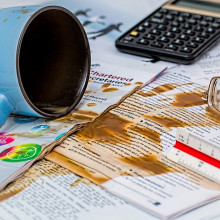 A mug of tea or coffee spilled over some papers.